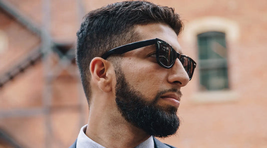 A man wearing sunglasses and formal wear with bow tie.