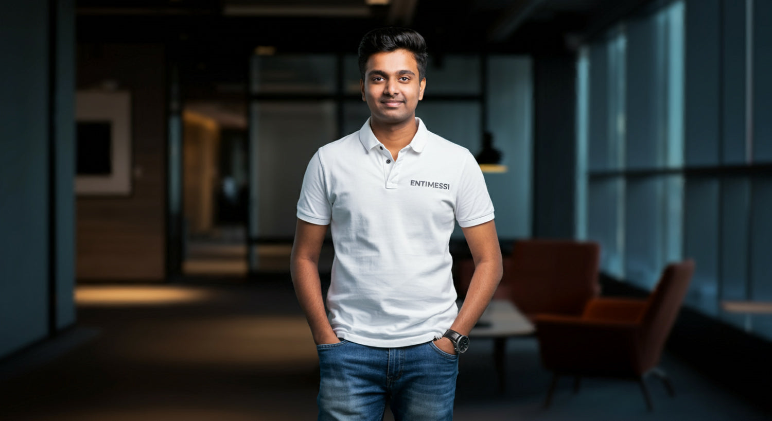 A young man, dressed in a custom white polo shirt, strikes a confident pose in a professional office space