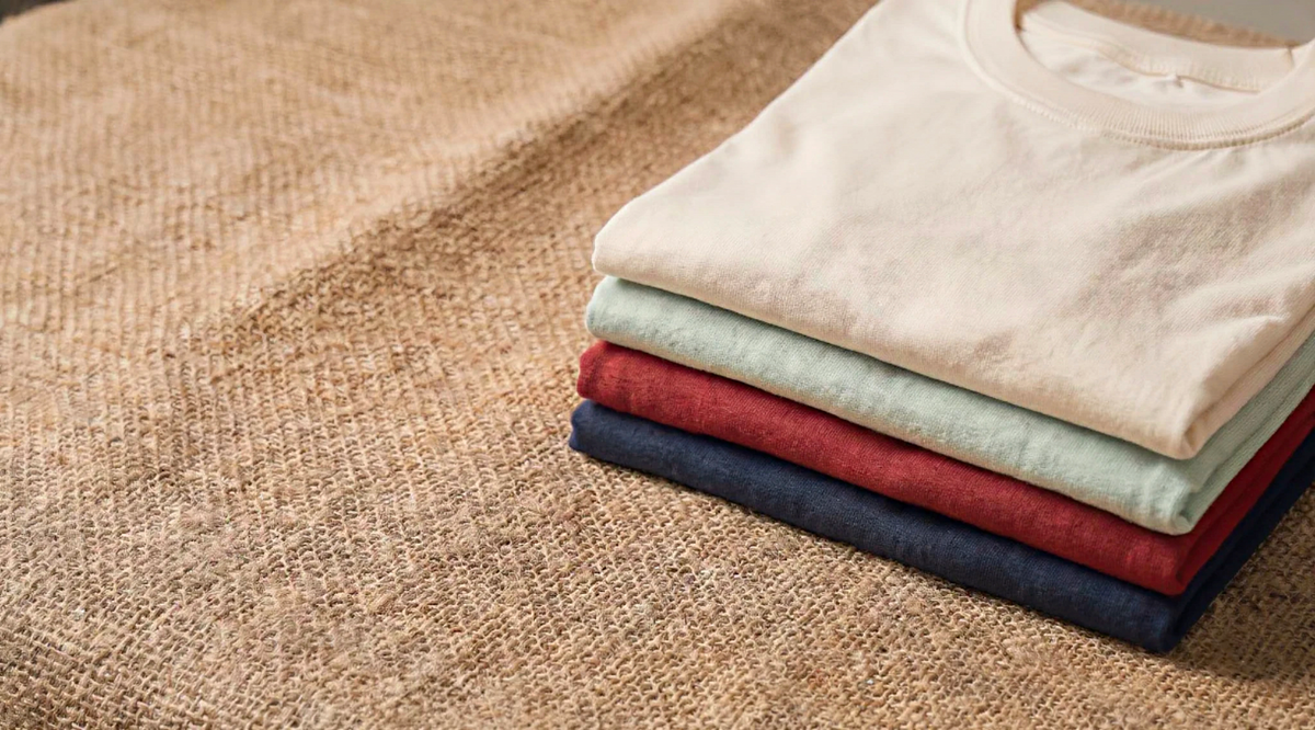 Stack of plain Entimessi cotton tees in off-white, mint, red and navy on jute